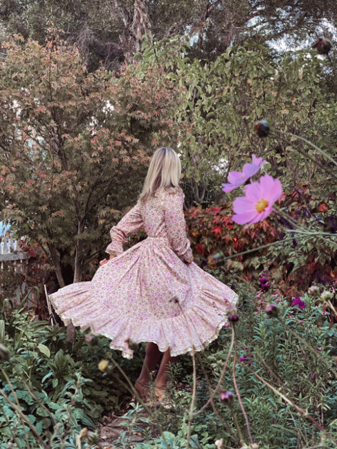 Fleur Harris standing in her garden wearing printed dress