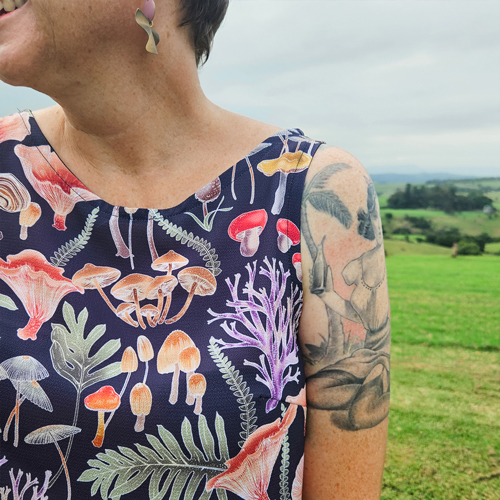 Kathryn Shaw of brand Rattamatatt wearing a printed top by Eloise Short. She is standing in a green field.