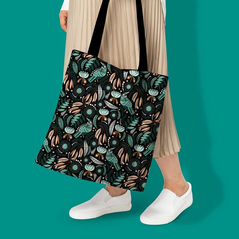 A custom printed tote bag is held in the hands of a woman on the tote bag is a bird print