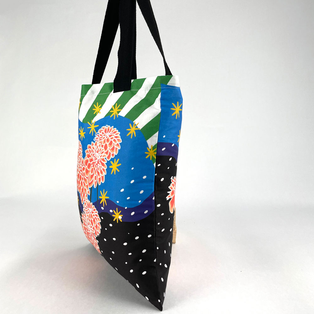 Side view of a custom printed tote bag with a modern floral design and black straps.