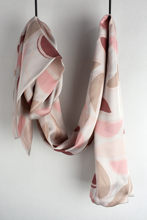 Satin scarf with a half circle design hanging in front of a white wall.