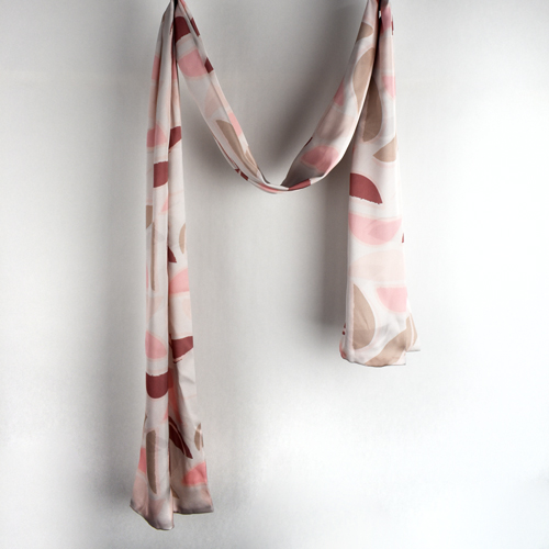 custom printed satin scarf elegently draped against a white studio wall.