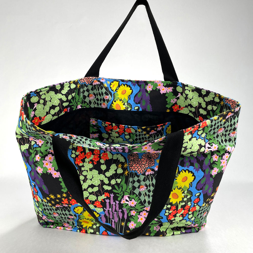 Detail shot of opened Harper Tote showing a full cover print of a bright floral design on a black background.