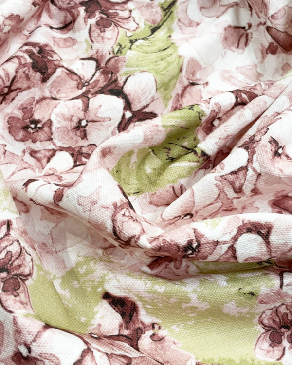 a close up of creased fabric in a cotton linene showing some pink hydrangeas printed on it.