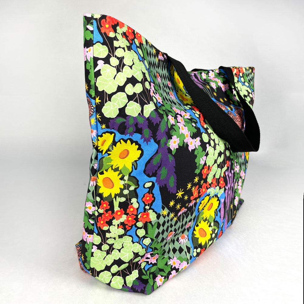 Side shot of opened Harper Tote showing a full cover print of a bright floral design on a black background.
